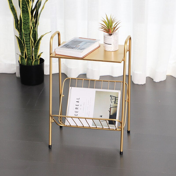 Gold sidetable with newspaper and a plant in the background